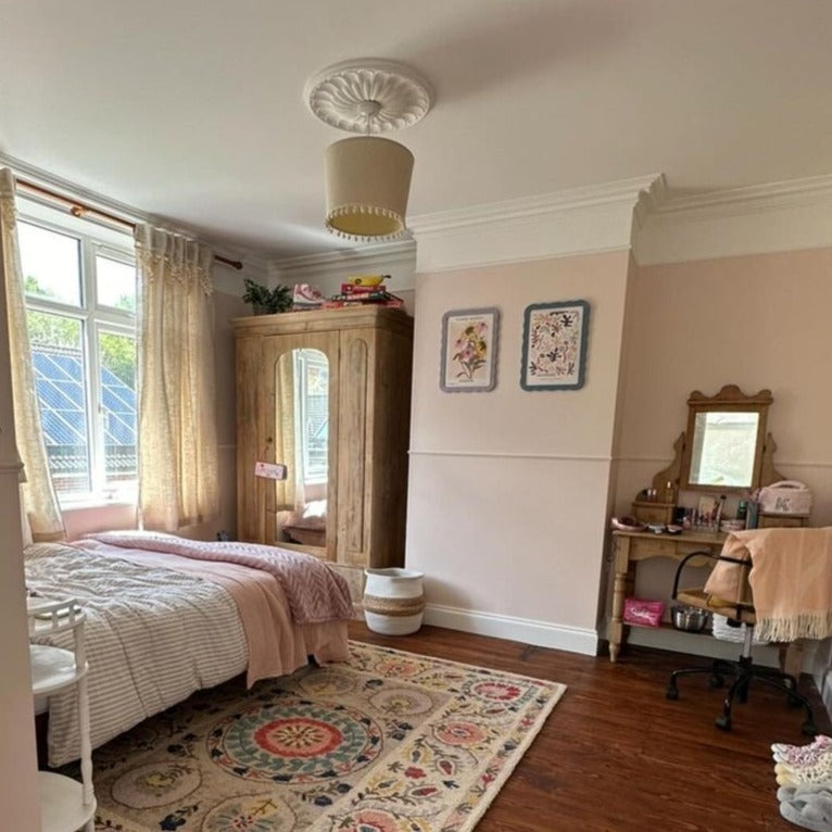 art deco plaster ceiling rose seen in pink bright bedroom with swan neck coving. 